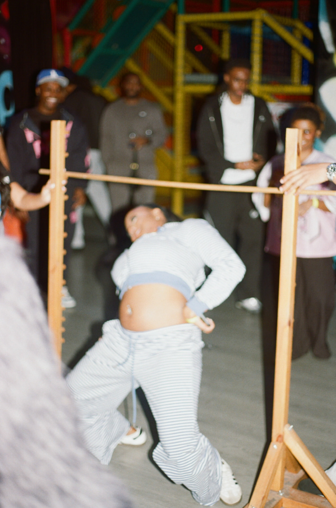 A player bending under a limbo bar while friends watch