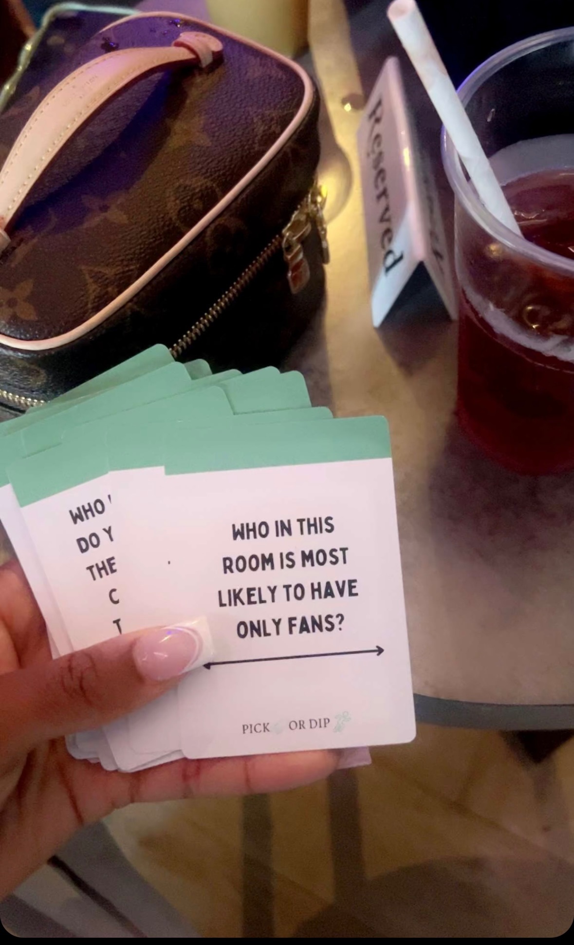A stack of Pick or Dip cards held at a restaurant table